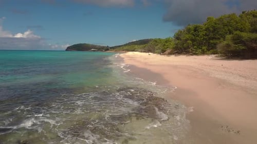 Aerial view along tropical beach as waves wash on shore