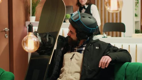 Snowboarder Relaxing in Stylish Hotel Lobby