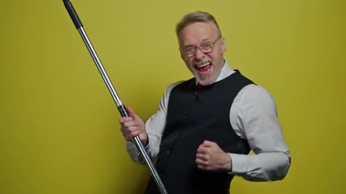 Man Mimes Playing Guitar in Front of Yellow Backdrop