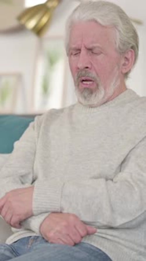 Sick Old Man Coughing Sitting on Sofa, Vertical Video
