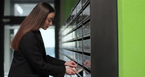 Woman is Opening Her Mailbox Inside a Cluster of Mailboxes for Her Apartment Mail Shipping Concept