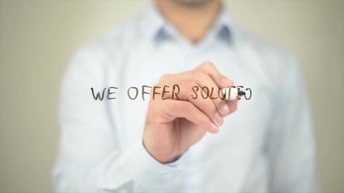 Man Writing "We Offer Solutions" on Glass