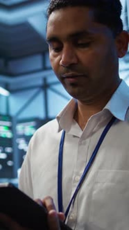 Young Adult Types on Tablet in Server Room