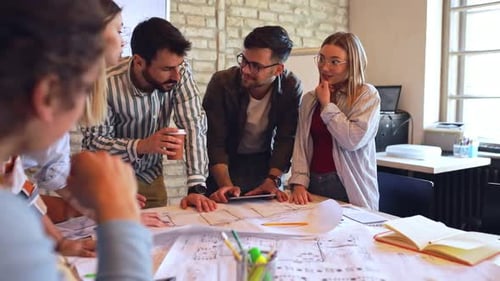 Group of young business people discussing architectural designs in office.
