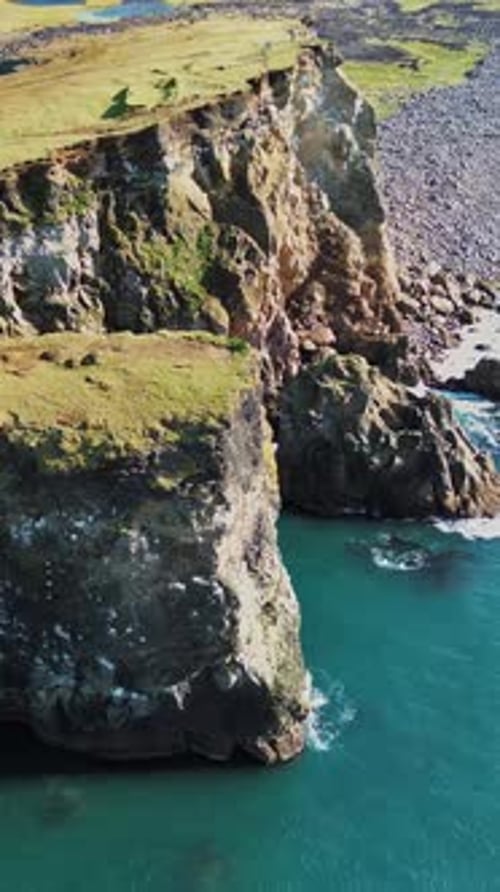 Aerial drone view of dramatic sea cliffs rising above the North Atlantic Ocean. Steep volcanic rock