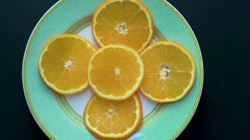 Blick von oben auf Orangenscheiben auf einem Teller, während sich die Kamera dreht.