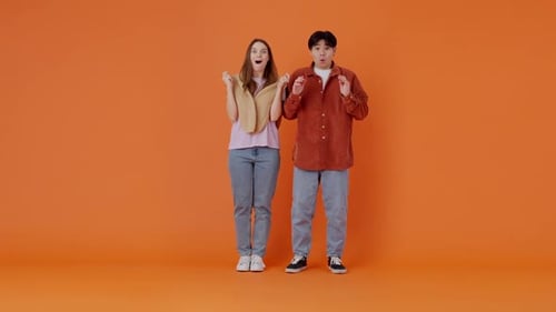 Surprised Man and Woman Reacting on Orange Background