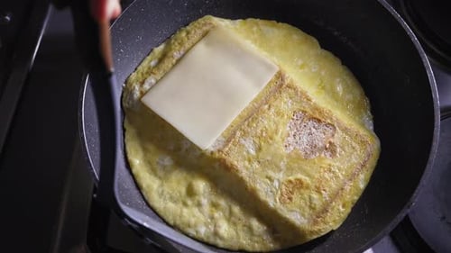 Person is adding cheese to his warm egg and cheese sandwich, cooking lunch - Steady Shot
