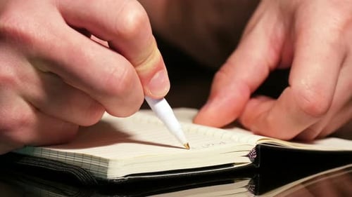 Male Hand Writing in Notebook with Pen at Evening