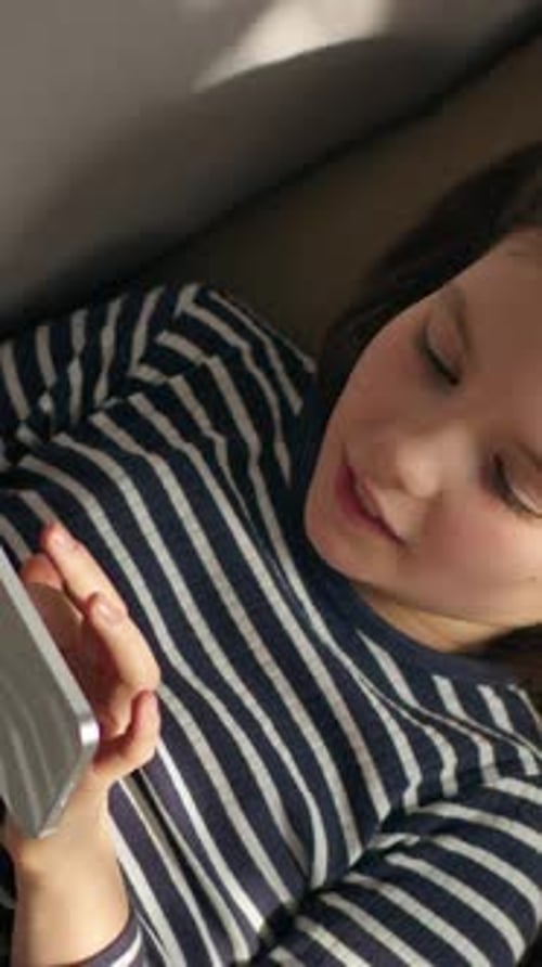 Top View Relaxed Caucasian Little Girl Child Kid Daughter Typing Message with Mobile Phone Texting