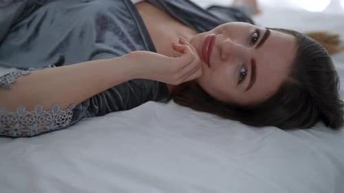 Attractive Woman Lies on Bed, Smiling