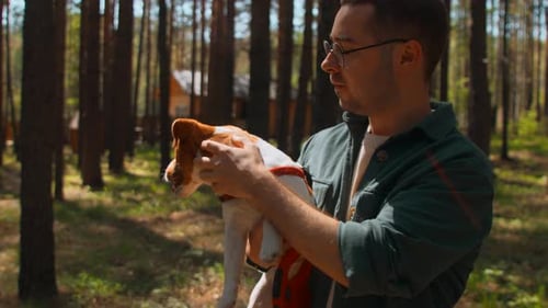 Man Holds Jack Russell Terrier in Forest