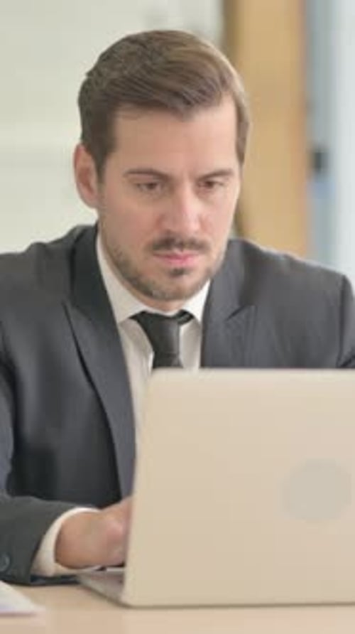 Geschäftsmann verlässt das Büro, nachdem er den Laptop geschlossen hat, vertikales Video