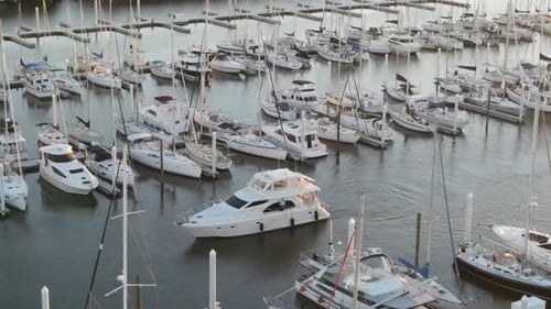 Private Yacht Cruising Between Moored Boats In Marina. - aerial