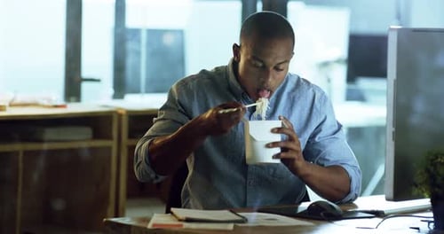 4k video footage of a young businessman eating takeout while working late in an office