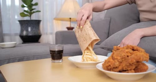 Pouring French Fries next to Fried Chicken and Cola