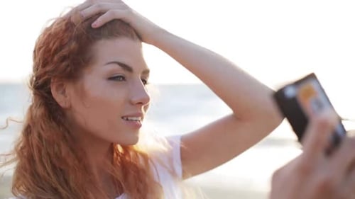 Woman takes selfie with mobile phone on beach