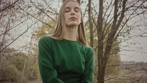Model posing touching her shoulder wearing green sweater
