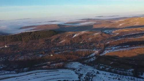 Aerial view of sunset over misty winter mountains