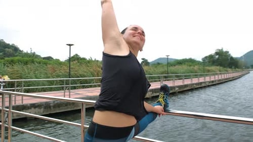 Woman Stretching Leg on Lakeside Path