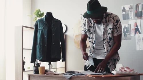 Nahaufnahme eines Designers, der verschiedene Stoffarten für die Modeskizze ausprobiert, findet die