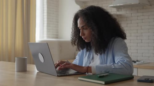 Woman Working on Laptop Computer at Kitchen Table