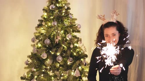 Woman Celebrating Christmas with Sparkler and Tree