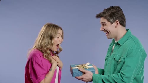 Young Woman Receiving Birthday Gift From Smiling Man