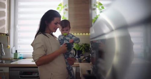 Mother Holding Her Baby Drinking From a Mug