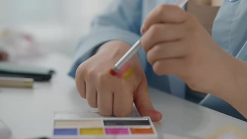 Closeup View of Young Lady Hands and Bright Eyeshadow Palette in Beauty Studio Professional Makeup