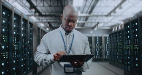 Big Data Center with Server Racks Specialist Using Tablet Computer Activating Servers