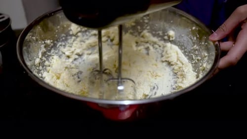 Electric Mixer Whisking Dough Mixture in a Large Stainless Steel Bowl. slow motion