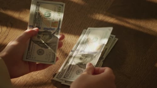 Counting Hundred Dollar Bills on Wooden Surface