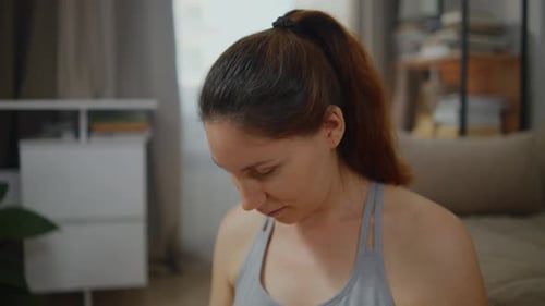 A Woman Massaging Her Neck with Rotating Movements at Home on a Yoga Mat
