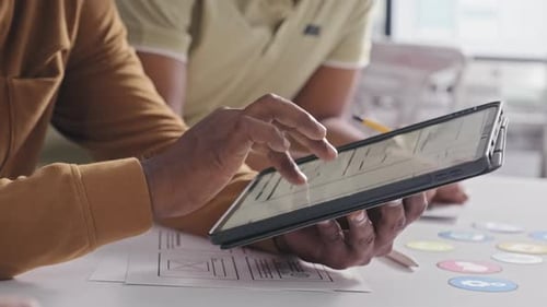 UX Designer Showing Mobile App Interface Sketch on Tablet