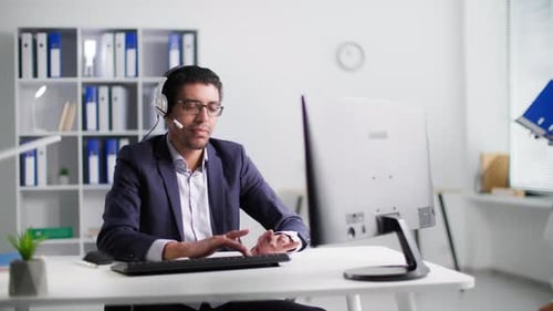 Customer Support Center Young African American Man with a Headset in Glasses is Talking to Man and