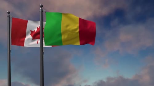 Canada And Mali Flags Waving On Flagpoles Against Blue Sky
