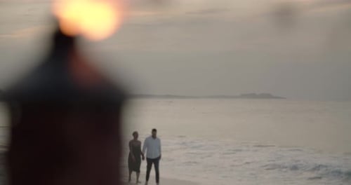 Couple on tropical beach at sunset walking near tiki torches in paradise
