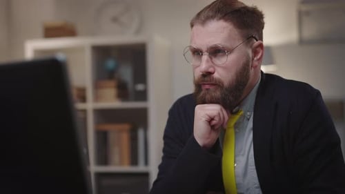 Bearded Man with Glasses Works on Computer