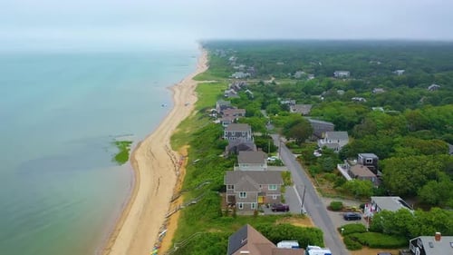Cape Cod coastline aerial view of beach houses at high tide with boat offshore under clouds