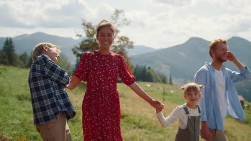 Cheerful Parents Smiling Walking with Children on Green Grass Mountain Valley. Carefree