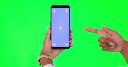 Woman, hands and phone mockup on green screen pointing for advertising against a studio background