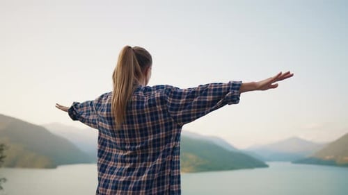 Carefree Woman with Wide Spreaded Arms Enjoying Breathtaking View of River and Mountains in Wild