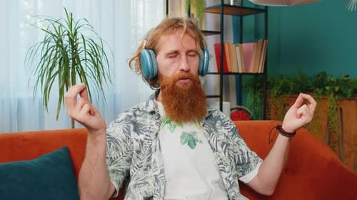Redhead Man Listening Music Breathes Deeply Meditating with Concentrated Thoughts Peaceful at Home