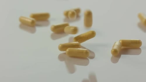 yellow medication tablet pills falling down on white clean pure surface in slow motion