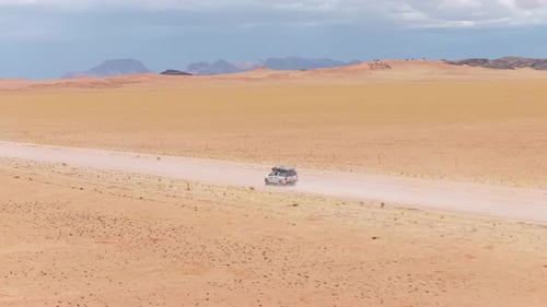 White Suv Driving on Dusty Off Road Trail Through Namib Desert in Namibia Creating Trail of Dust in
