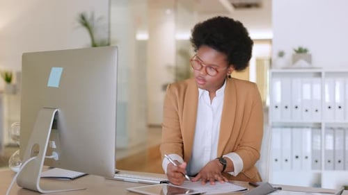 Woman Working At Computer And Writing At Desk