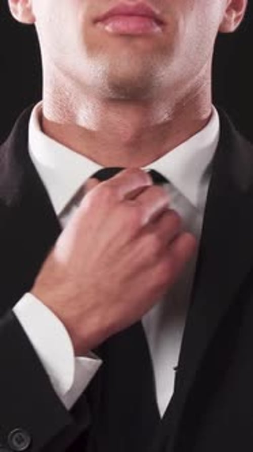 Man in Suit Adjusting Tie, Smiling