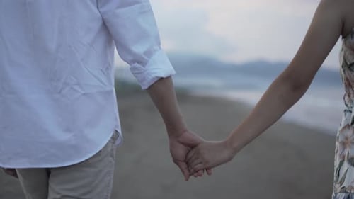 Couple Walks Hand in Hand on Beach