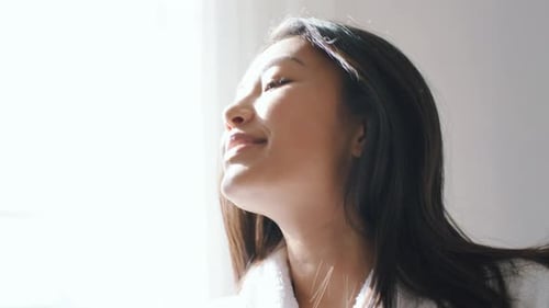 Woman in Robe Enjoys Sunlight Indoors
